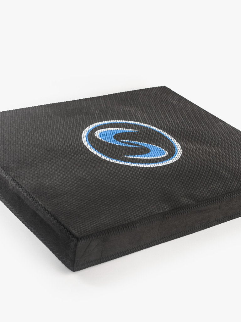 An angled shot of a black stability pro mat with a blue logo, designed for use in kneeling swings and stability training.